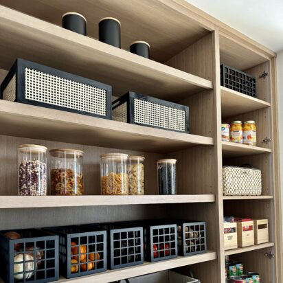 Modern pantry organization with labeled containers, baskets, and neatly arranged food items