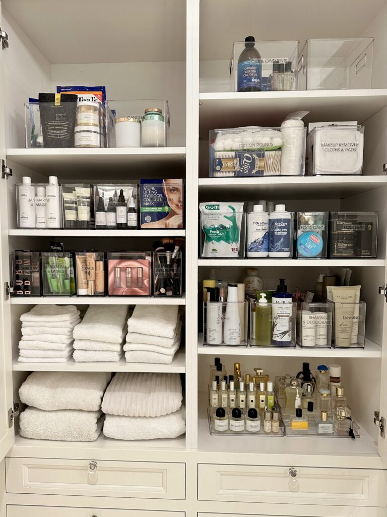 Organized cabinet with neatly folded towels, labeled bins, and household supplies
