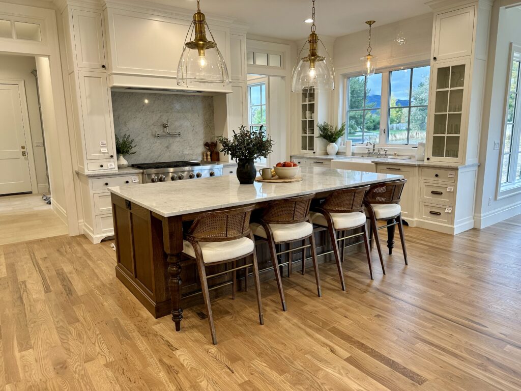 Modern kitchen with large island, barstools, pendant lights, and white cabinetry