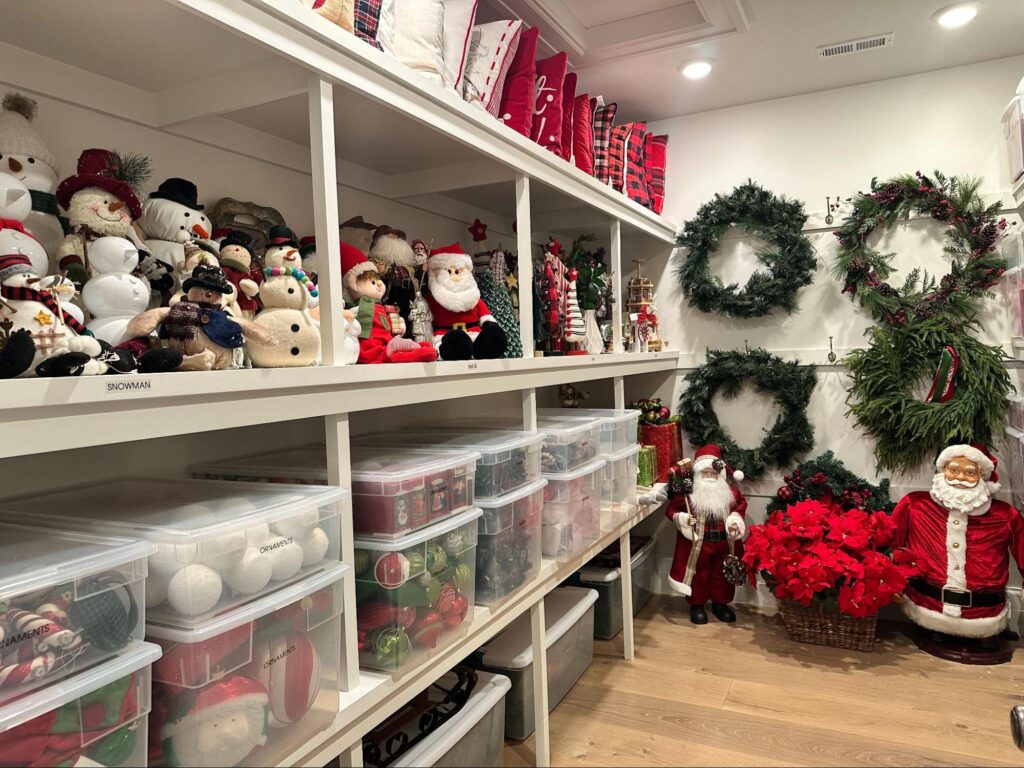 Holiday storage room with clear bins, wreaths, and seasonal decorations neatly arranged.