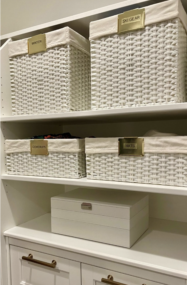 Closet shelves with white woven baskets labeled winter, ski gear, coverups, and hats, plus a white storage box.