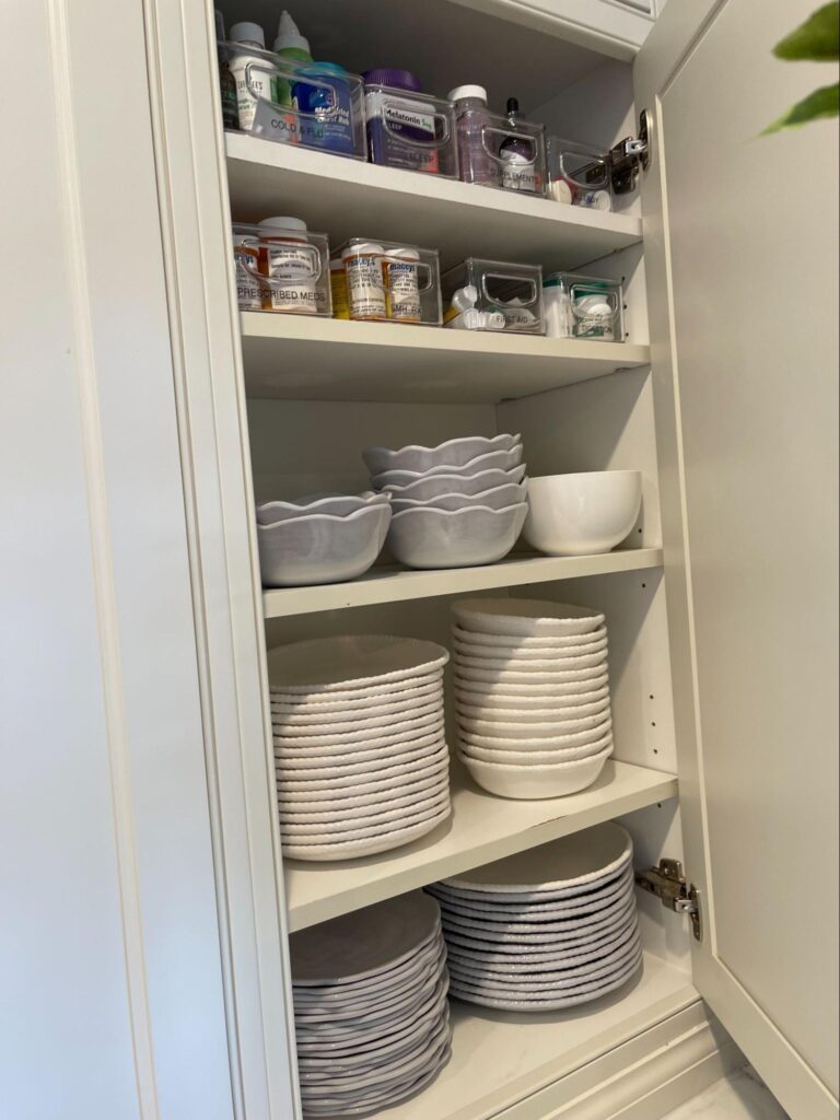 Organized pantry shelves with neatly stacked dishes, bowls, and labeled containers.