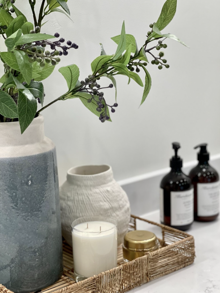 Bathroom organization ideas - Home Organization Bathroom countertop styled with decorative greenery, soap dispensers, candle, and small tray for a calm, minimal look