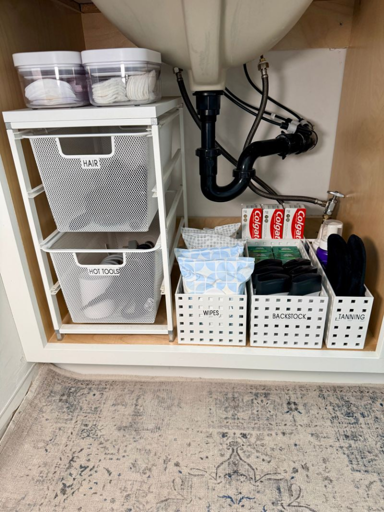 Bathroom organization ideas - Home Organization Organized under-sink cabinet with stacked storage bins holding cleaning supplies, extra toiletries, and household items