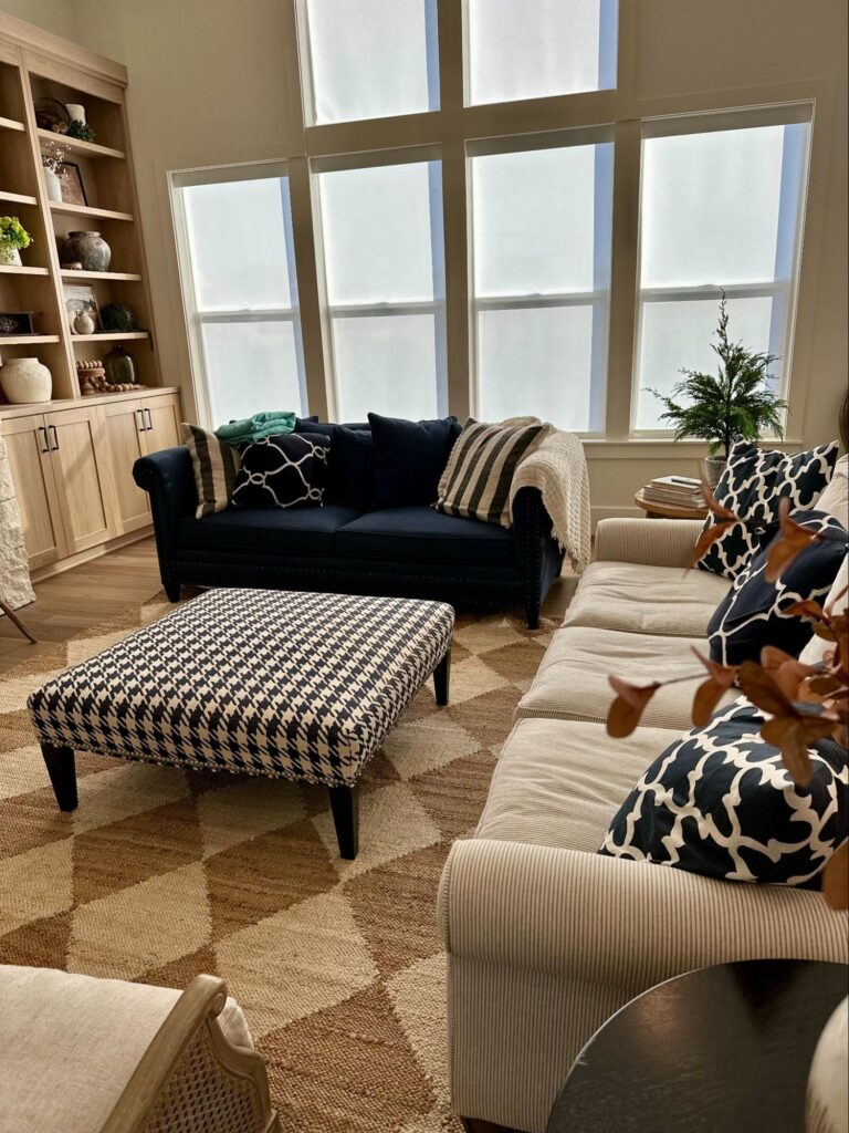Spring cleaning checklist - Home Organization Cozy living room with sofas, patterned ottoman, built-in shelves, and large windows