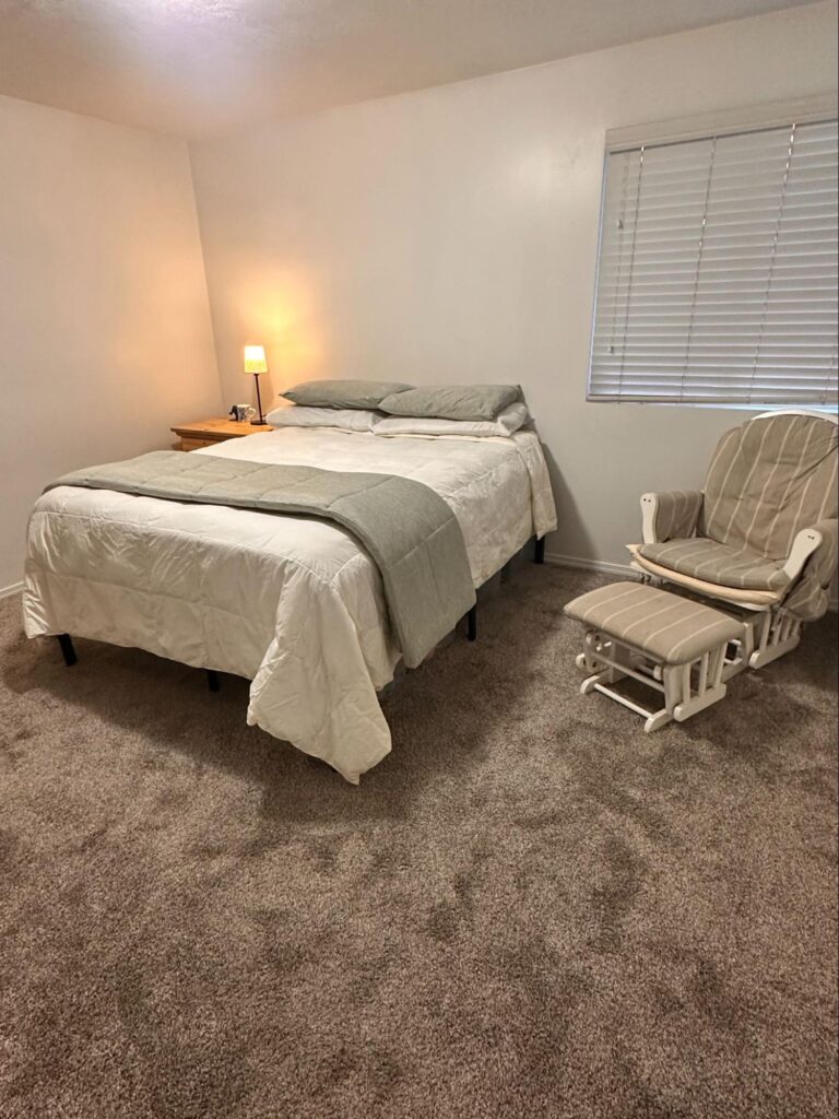 Spring cleaning checklist - Home Organization Simple bedroom with neatly made bed, bedside lamp, and chair near window