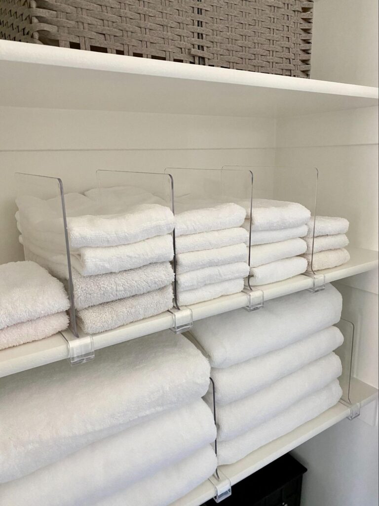 linen closet organization - Home Organization Folded white towels organized on shelves with clear dividers keeping stacks neat and separated