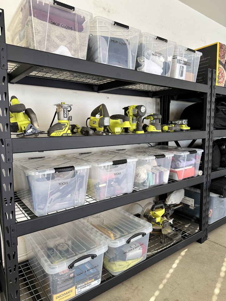 Garage shelving with clear labeled bins and neatly arranged power tools on metal racks.