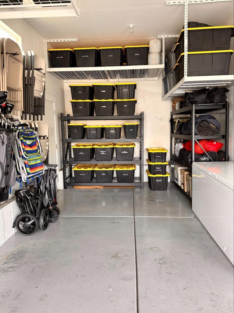 Organized garage with overhead racks, shelving, and stacked storage bins