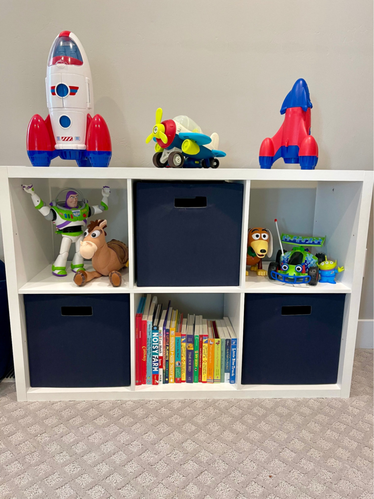 Toy rotation ideas - Kids bedroom organization Kids bookshelf and cube storage organizer with toy rockets, children’s books, and character toys neatly displayed.