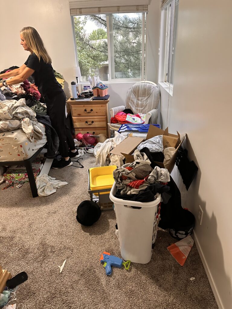 Bedroom filled with clothing and household clutter before decluttering