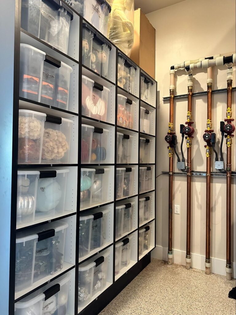 Floor-to-ceiling basement storage cabinets with numbered clear bins for organizing fall, Halloween, and Christmas decorations.