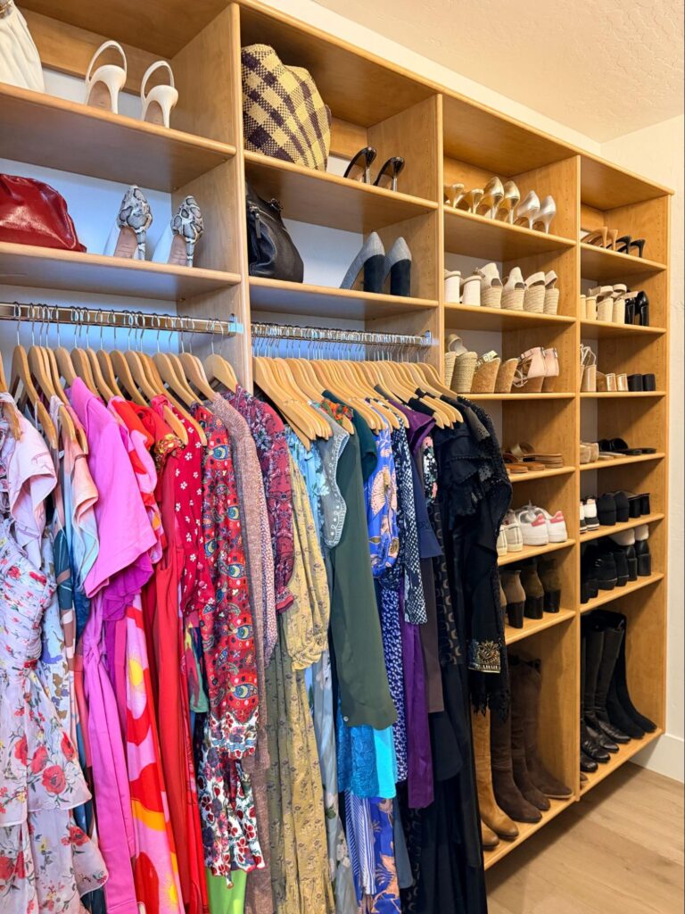 walk in closet organization - Closet Organization Walk-in closet with colorful clothing grouped on hangers and shoes organized on open wooden shelves.