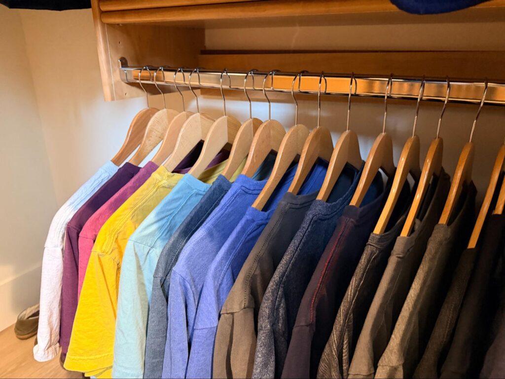 walk in closet organization - Closet Organization Men's shirts and jackets arranged by color on matching wooden hangers inside a walk-in closet.
